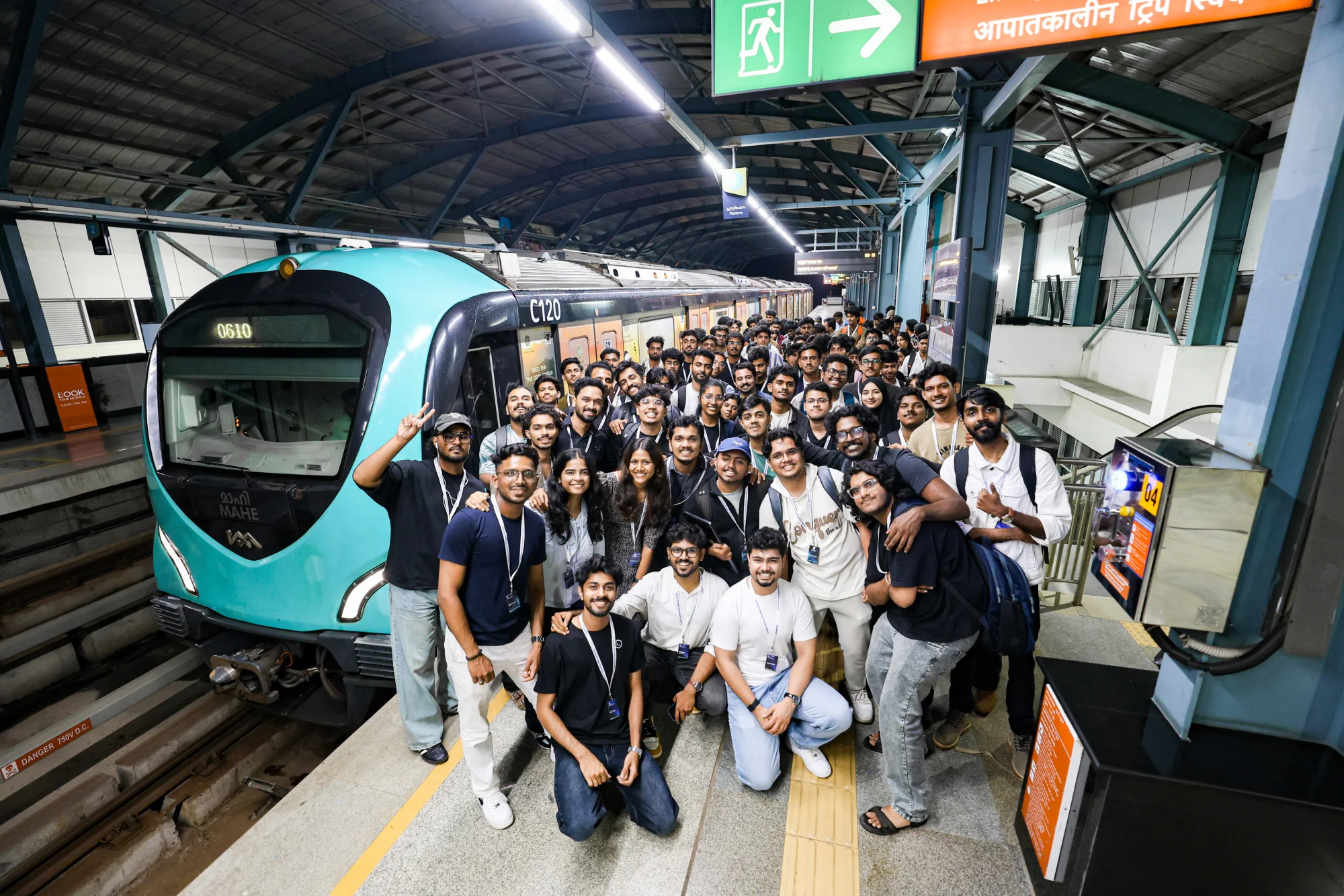 Codex Nightline builders gathered beside a Kochi Metro train