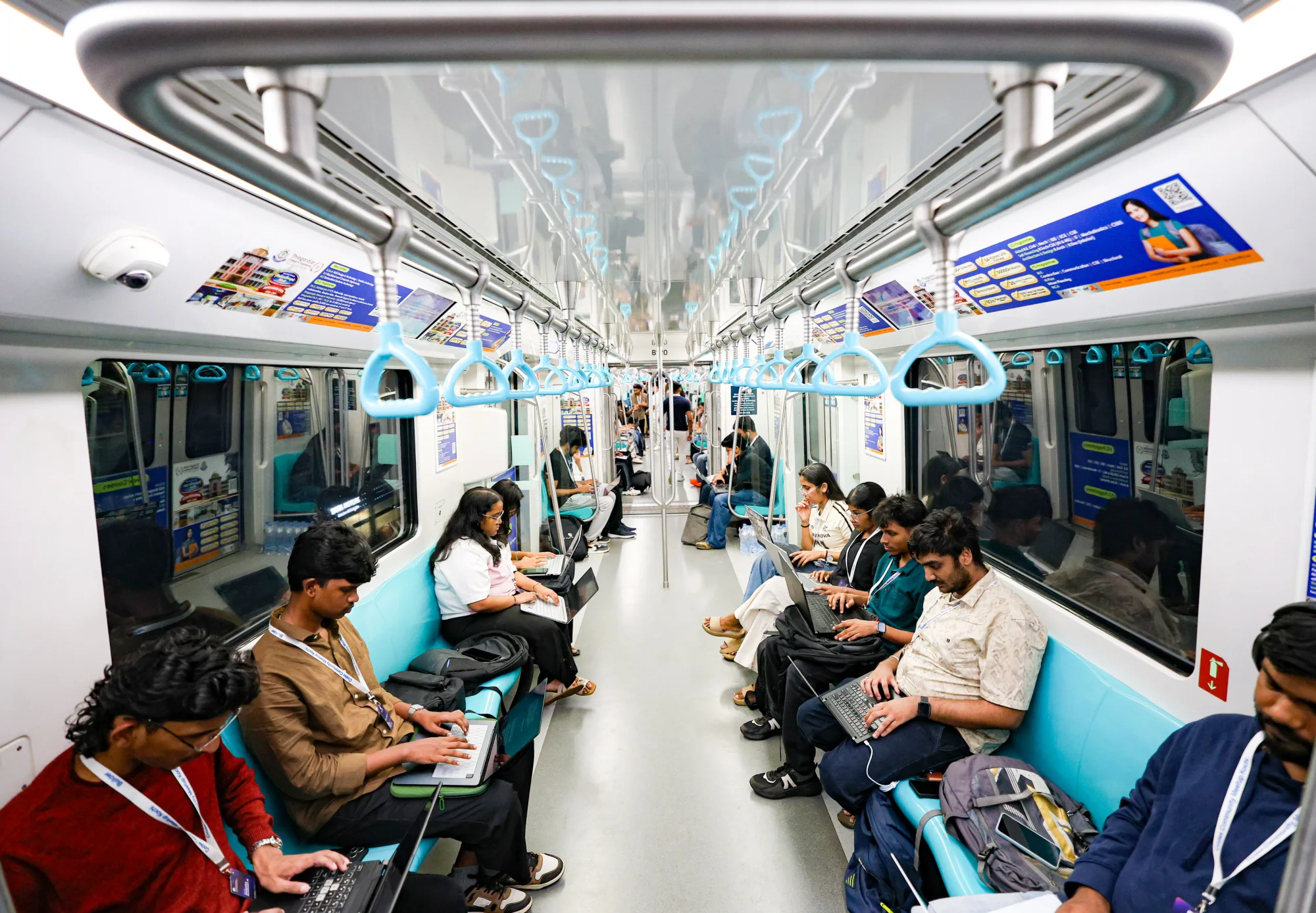Participants building with laptops inside a moving Kochi Metro train