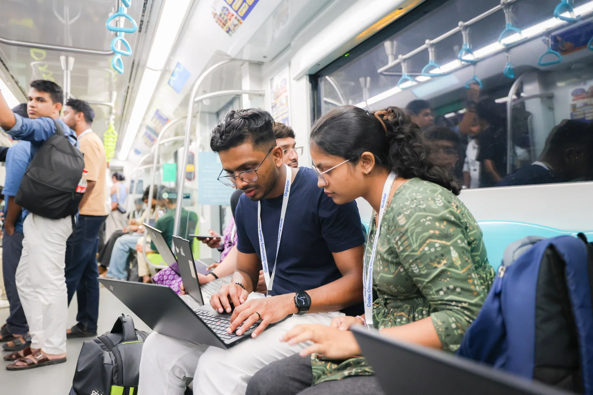 Two builders collaborating on a laptop onboard the metro